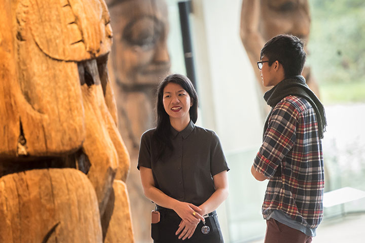Two people converse in the Museum of Anthropology's Great Hall at UBC's Vancouver campus