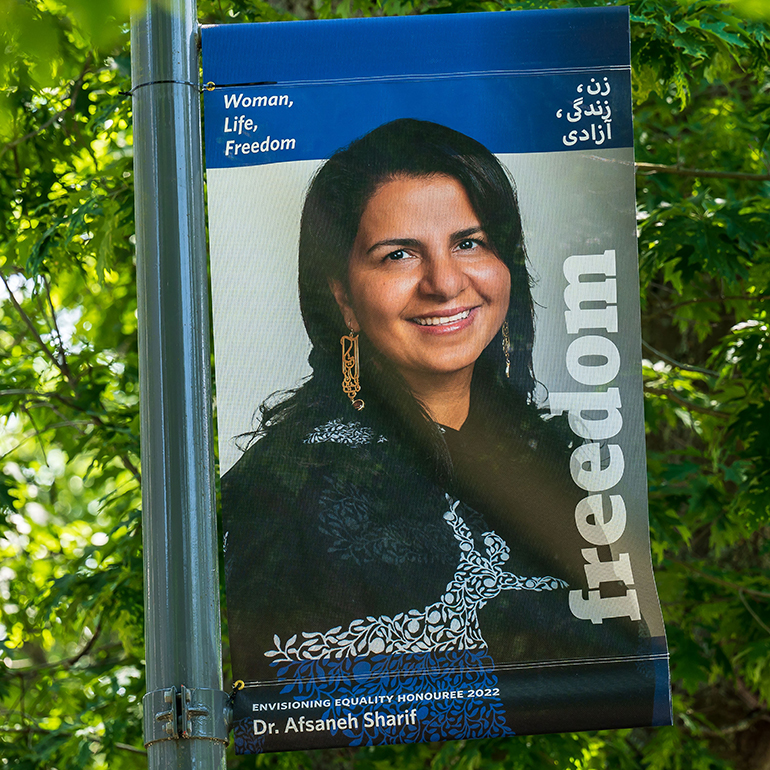 Dr. Afsaneh Sharif, pictured on a blue banner
